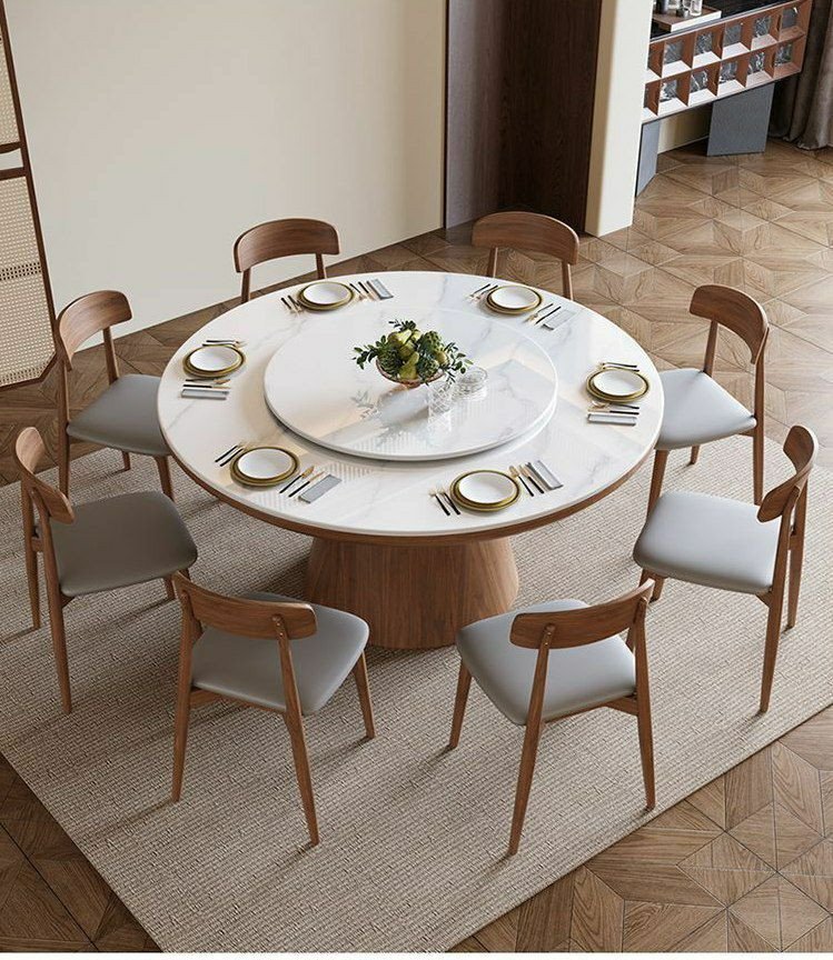 Table à manger ronde moderne en bois avec un plateau en pierre frittée et un plateau tournant central (type Lazy Susan), accompagnée de huit chaises assorties au dossier incurvé et à l'assise grise.